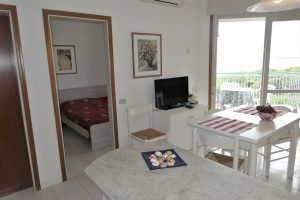 Salotto, terrazzo e camera da letto in appartamento a Lignano